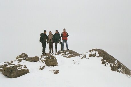 A snowy mountain ridge with four scientists on a misty background.